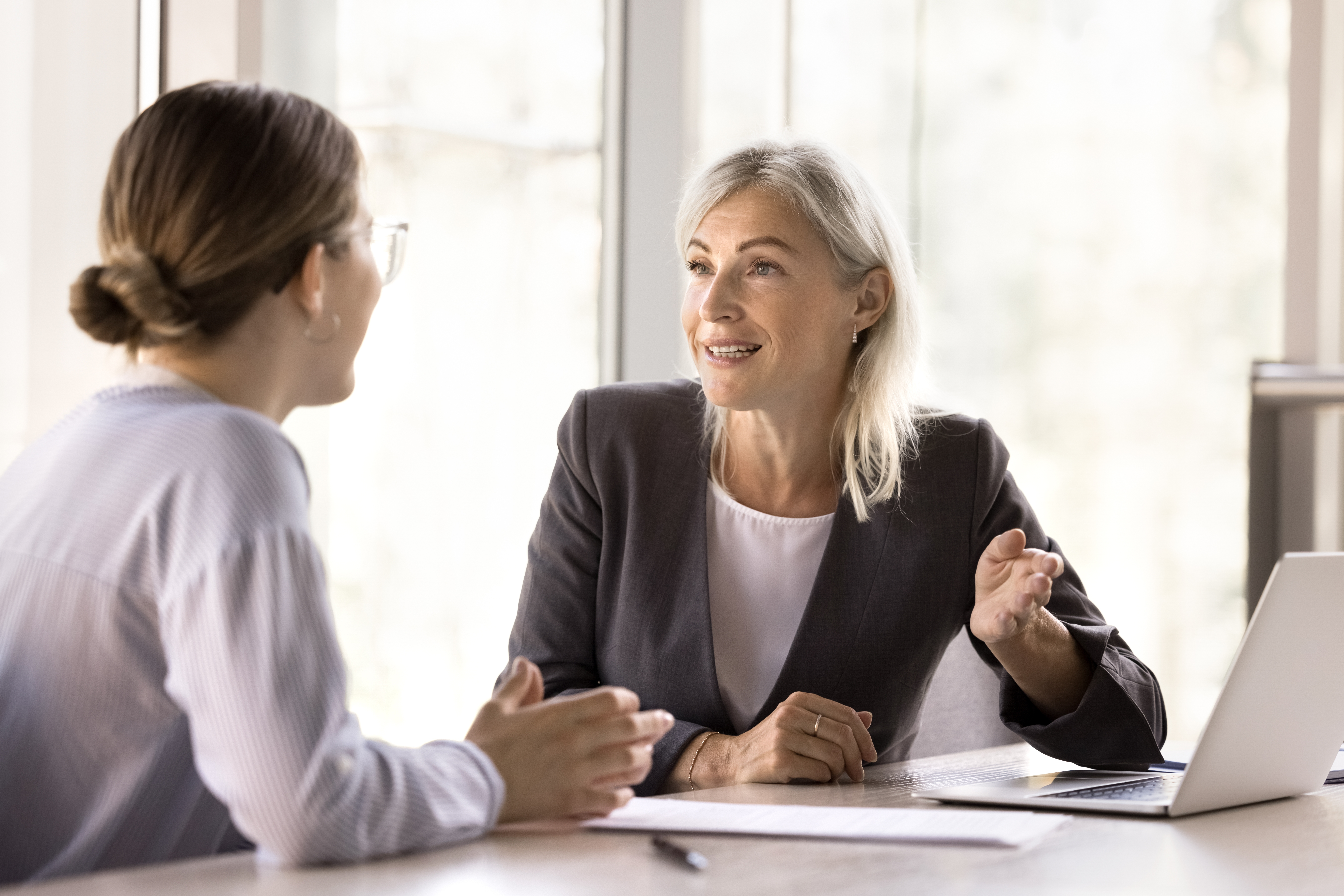 An older business professional mentoring her younger peer
