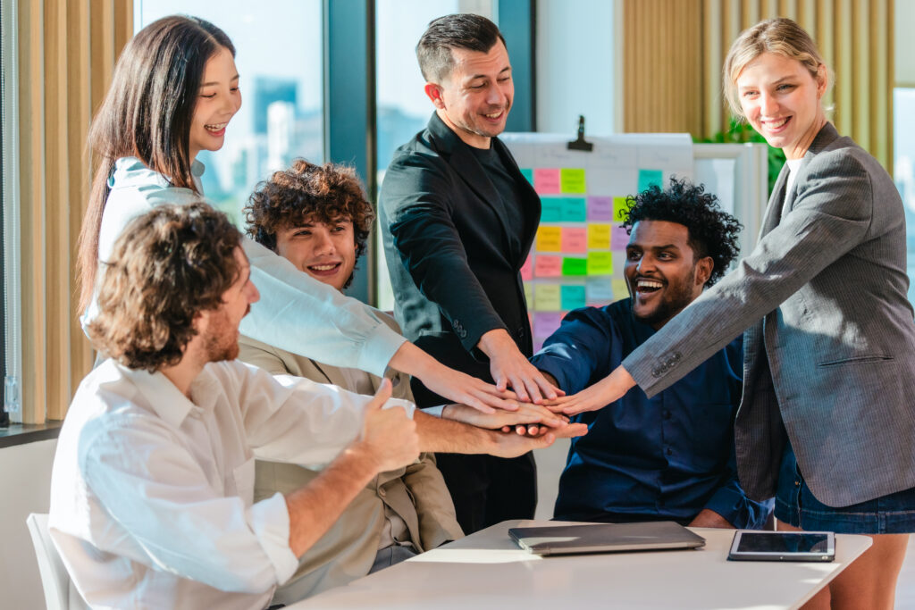 A team of multi-ethnic professionals joining hands after a meeting, demonstrating a positive work culture.