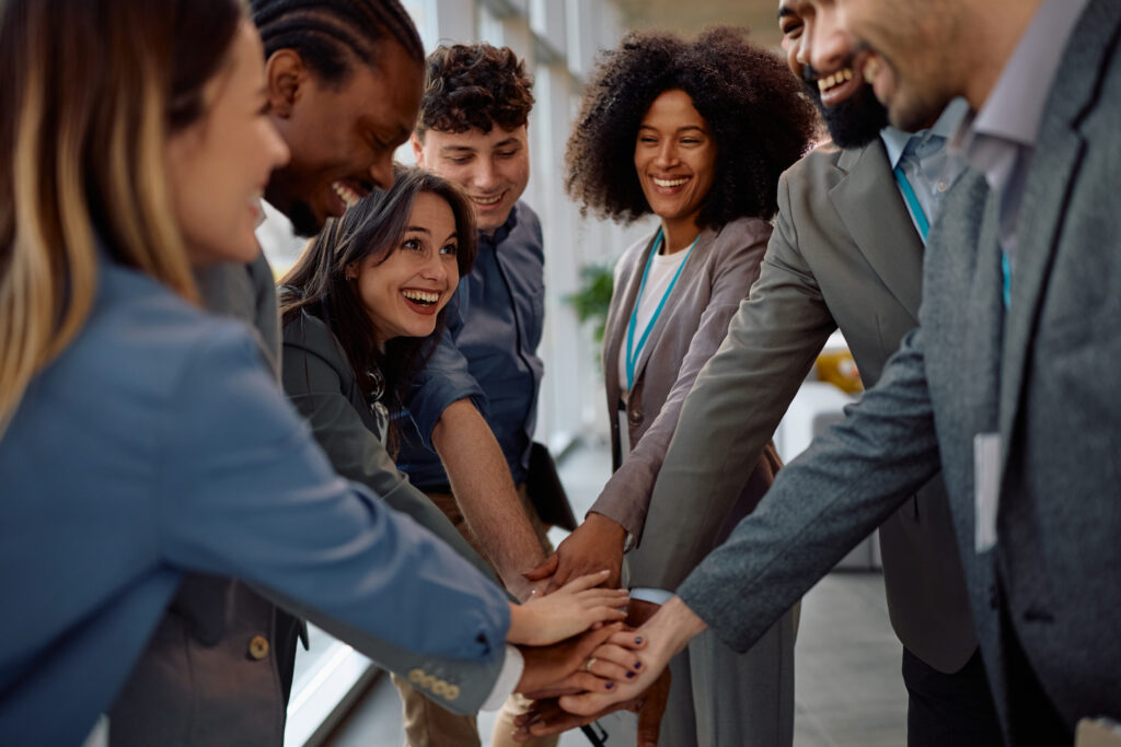 A multiracial team of business professionals with hands together, symbolizing teamwork and positive workplace culture