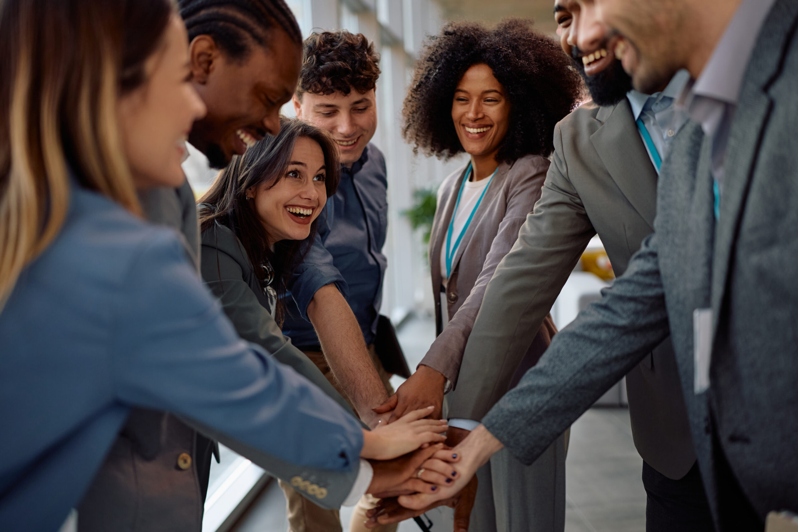 A multiracial team of business professionals with hands together, symbolizing teamwork and positive workplace culture